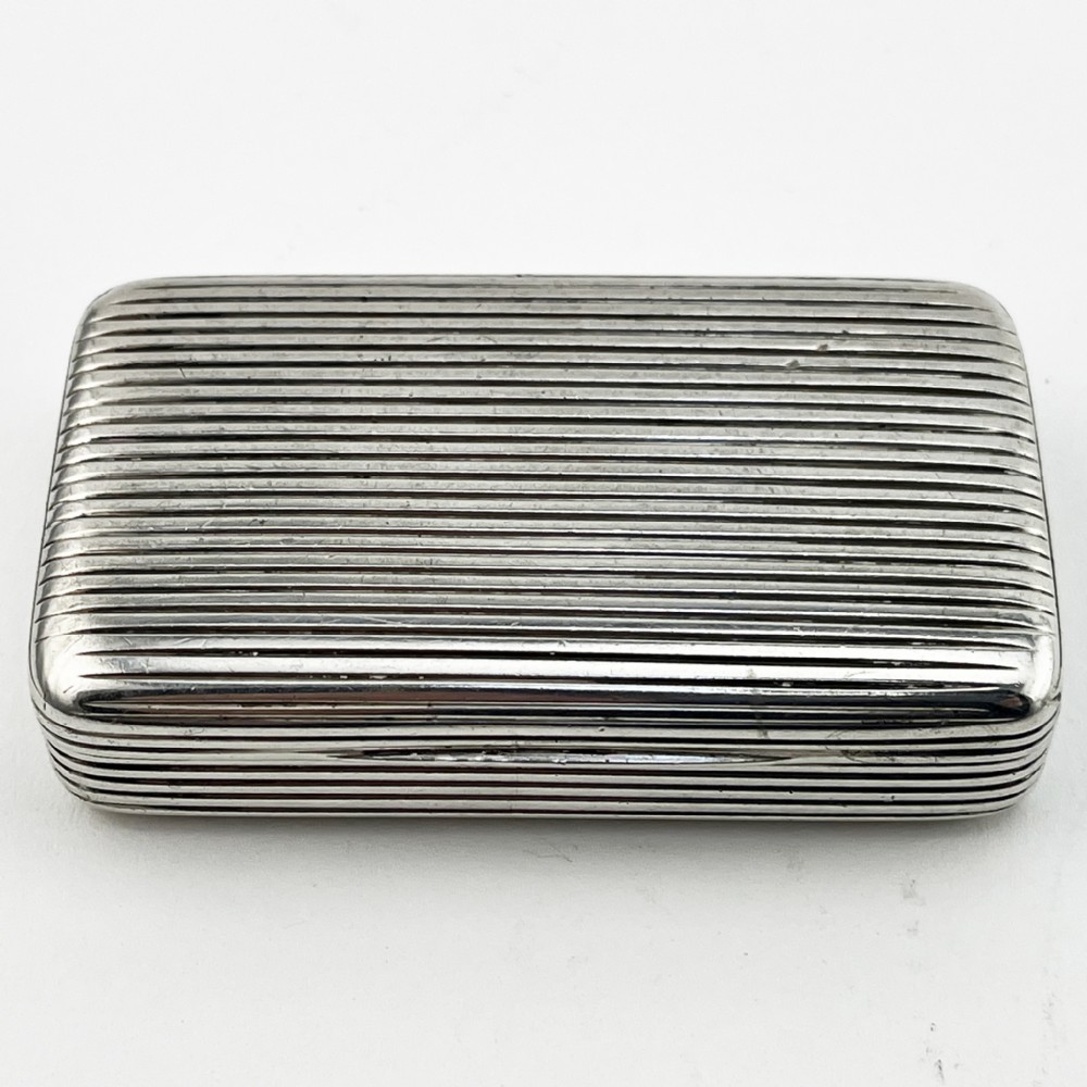 A small rectangular Georgian sterling silver snuff box with a hinged lid and horizontal reeded stripe decoration.