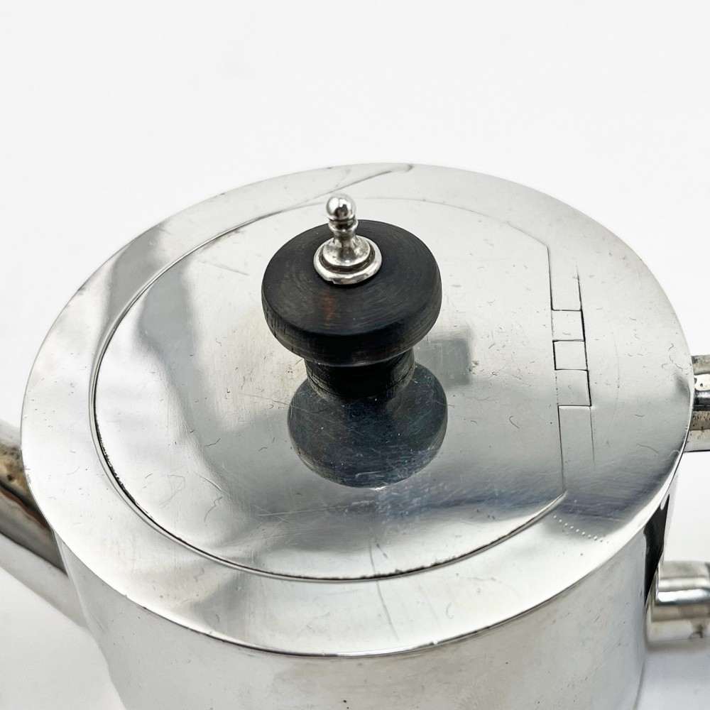 A Georgian sterling silver bachelor teapot featuring a cylindrical drum body, straight spout, and dark wooden handle and finial. View VI