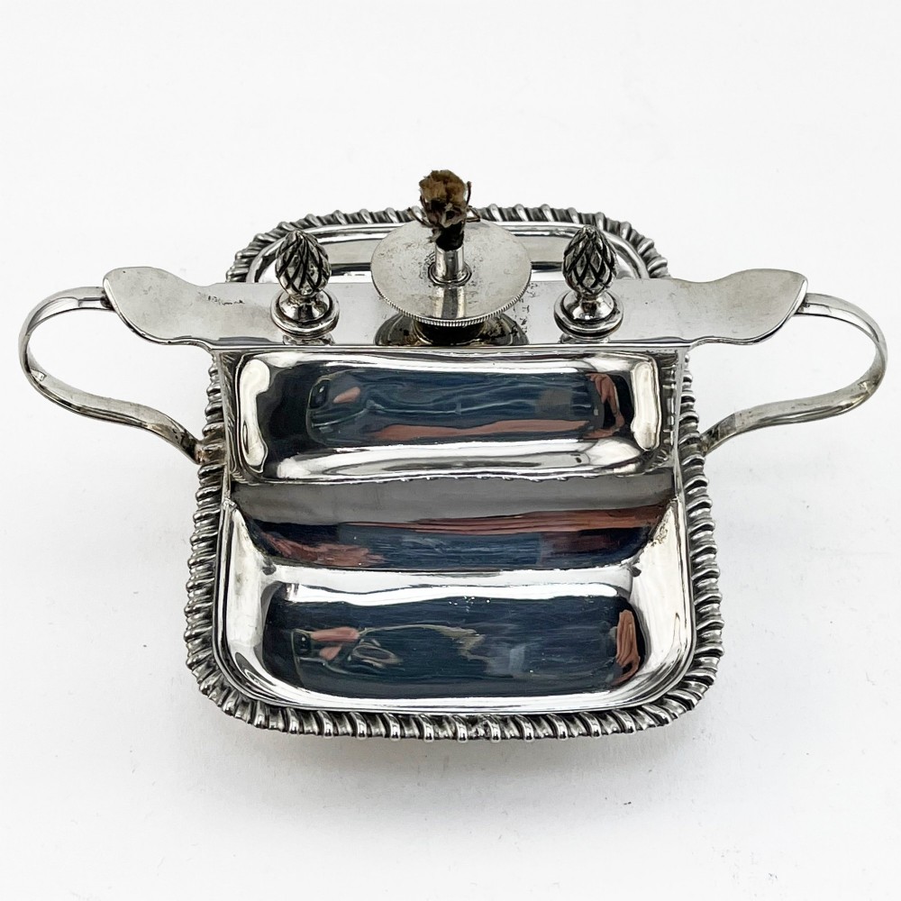 An Edwardian sterling silver table cigar lighter featuring a gadrooned tray border, central wick reservoir, twin handles, and hallmarks. View III