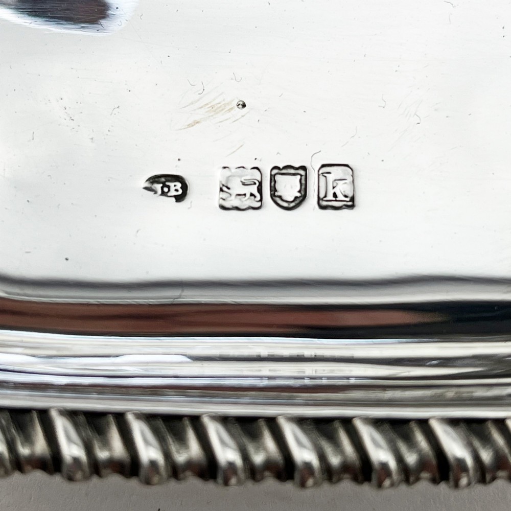 An Edwardian sterling silver table cigar lighter featuring a gadrooned tray border, central wick reservoir, twin handles, and hallmarks. View VII