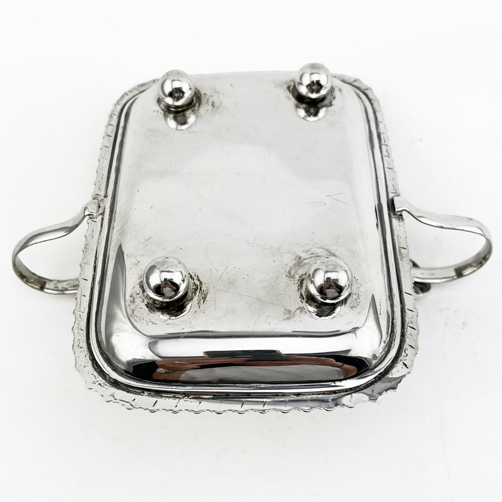 An Edwardian sterling silver table cigar lighter featuring a gadrooned tray border, central wick reservoir, twin handles, and hallmarks. View VIII