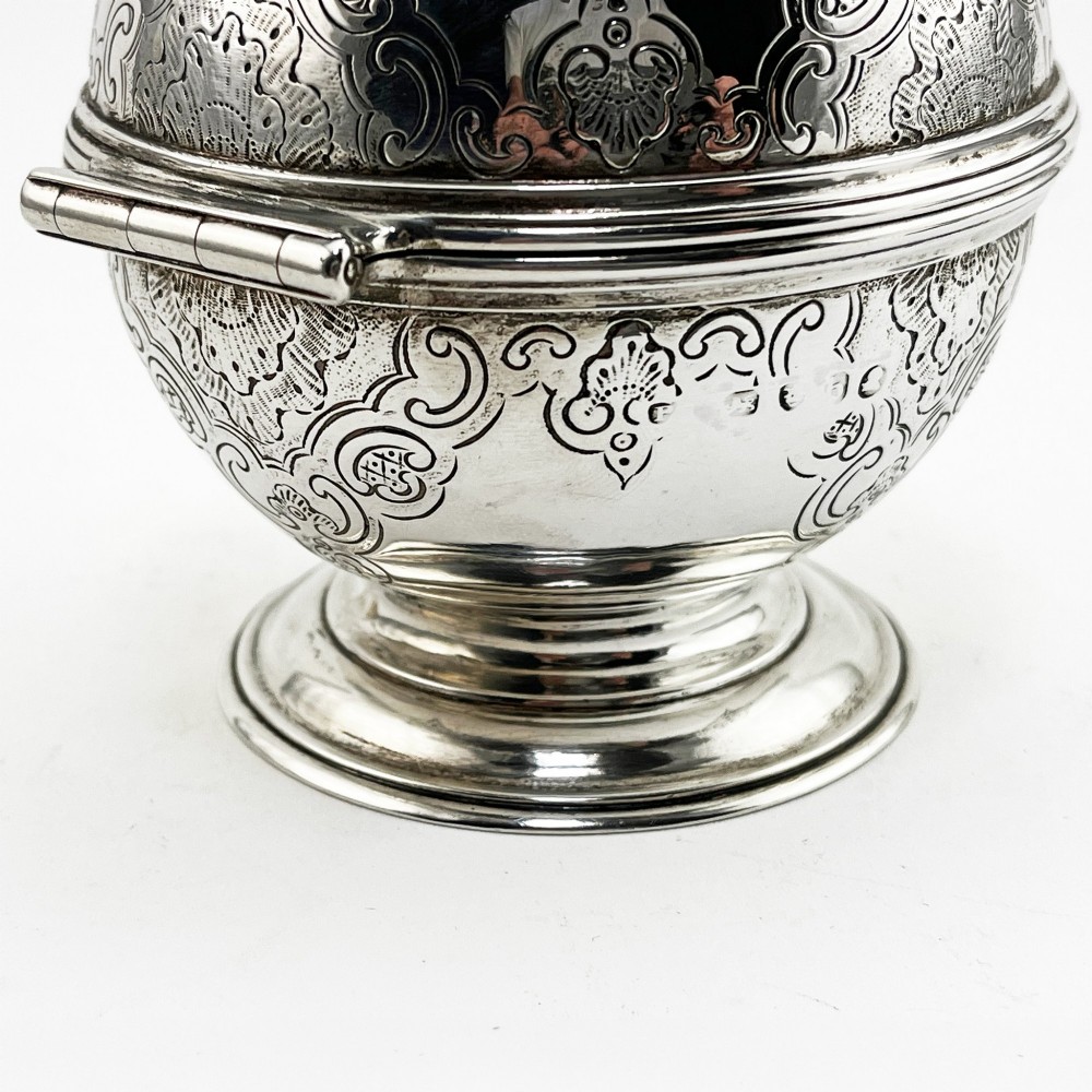 A spherical George III sterling silver soap box featuring engraved scrollwork and a finial shaped like two cherubs holding an orb. View IV