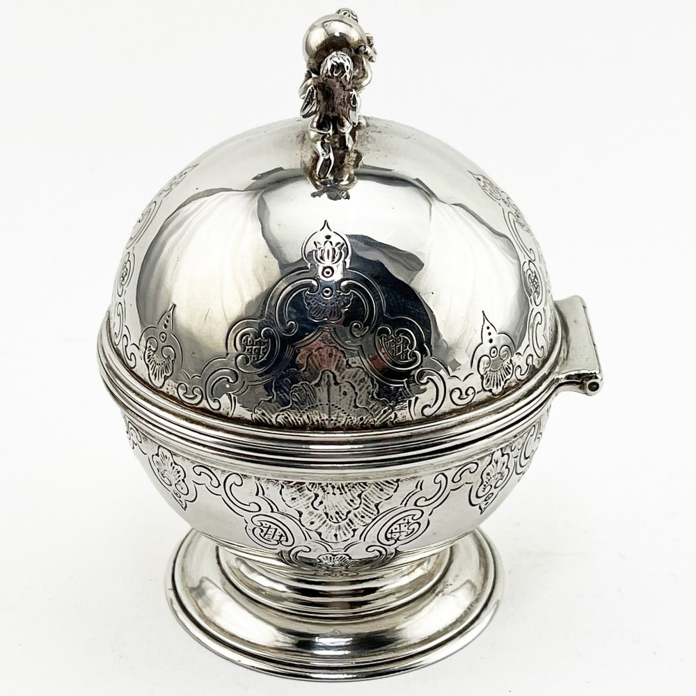 A spherical George III sterling silver soap box featuring engraved scrollwork and a finial shaped like two cherubs holding an orb. View V