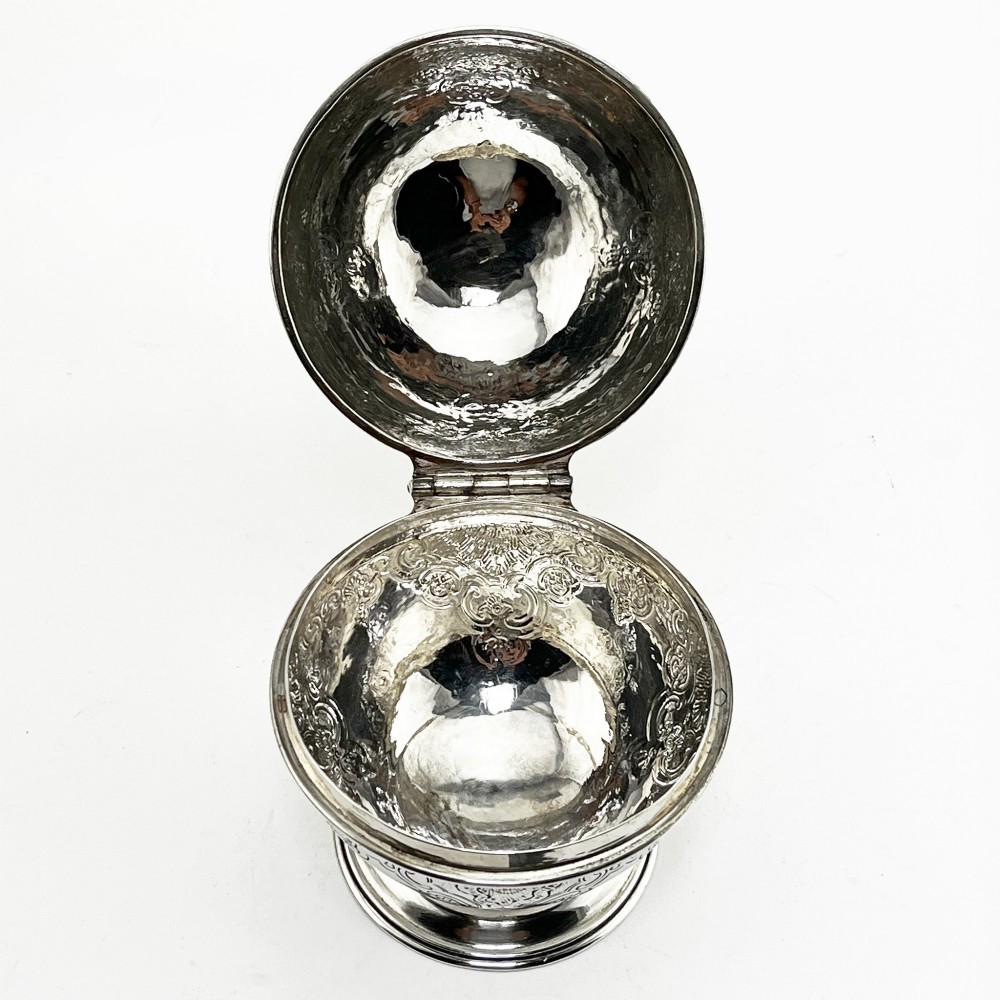 A spherical George III sterling silver soap box featuring engraved scrollwork and a finial shaped like two cherubs holding an orb. View VI