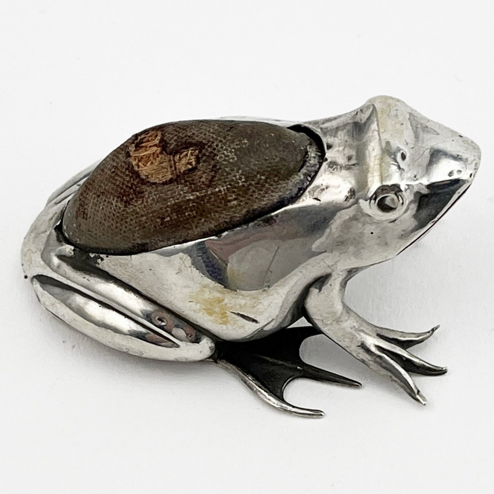 An Edwardian sterling silver pin cushion cast in the realistic shape of a frog with a dark fabric cushion inset on its back. View IV