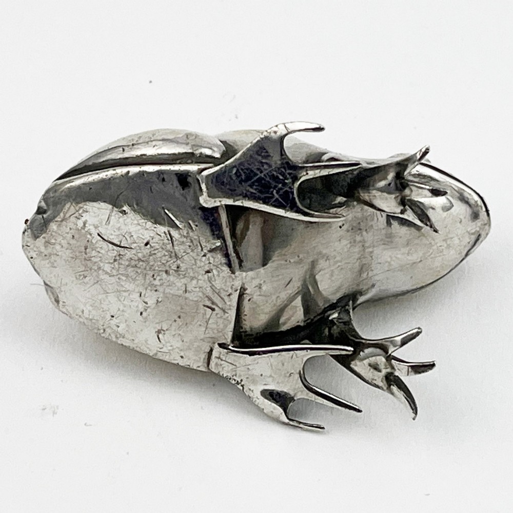 An Edwardian sterling silver pin cushion cast in the realistic shape of a frog with a dark fabric cushion inset on its back. View VI