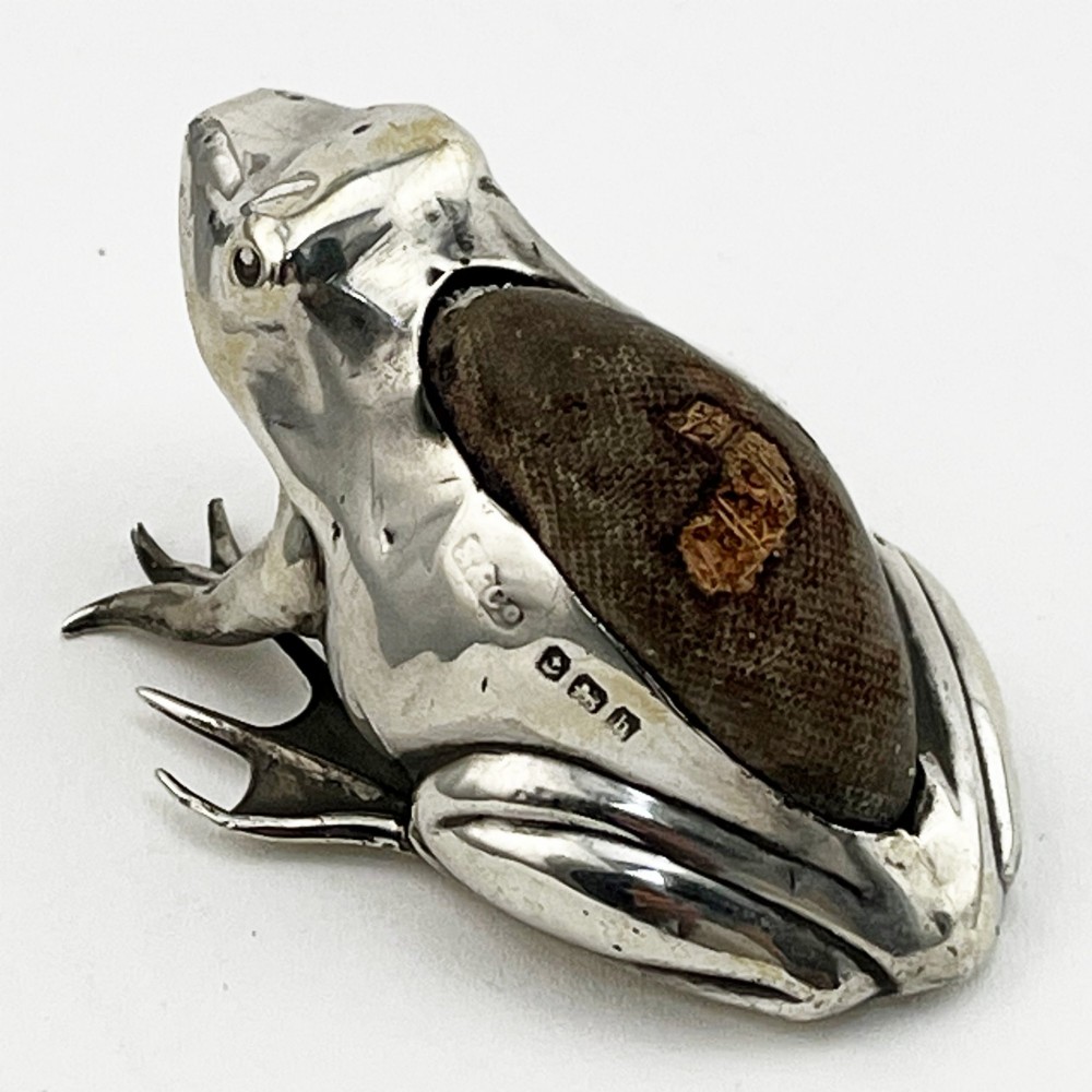An Edwardian sterling silver pin cushion cast in the realistic shape of a frog with a dark fabric cushion inset on its back. View VII
