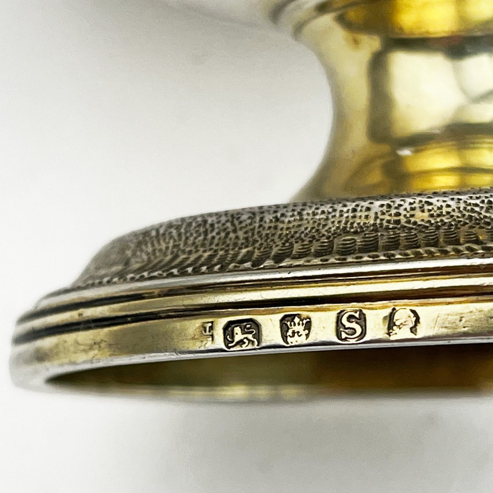 A George III sterling silver campana-shaped cup featuring chased floral motifs, a vacant cartouche, twin scroll handles, and a gilt interior. View VI