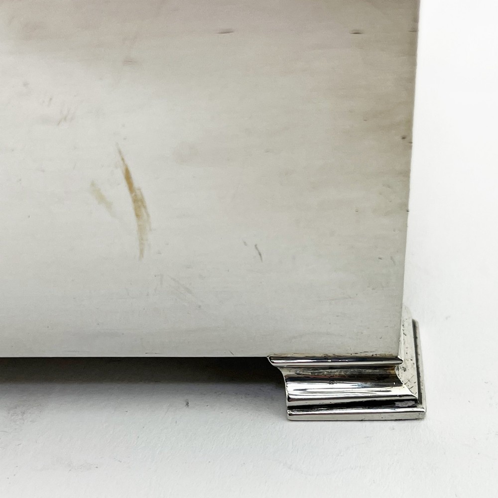 A rectangular sterling silver box featuring an engine-turned patterned lid, a central rectangular cartouche, and four stepped bracket feet. View V
