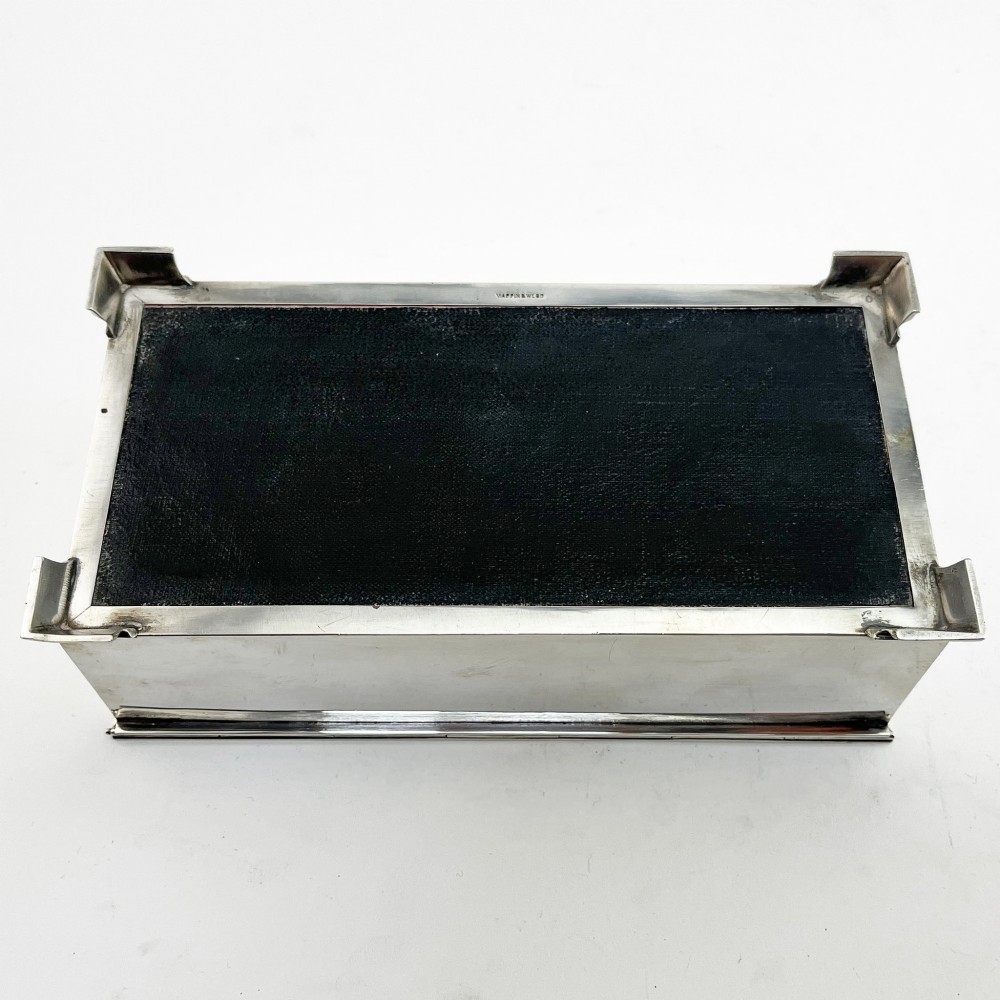 A rectangular sterling silver box featuring an engine-turned patterned lid, a central rectangular cartouche, and four stepped bracket feet. View VII