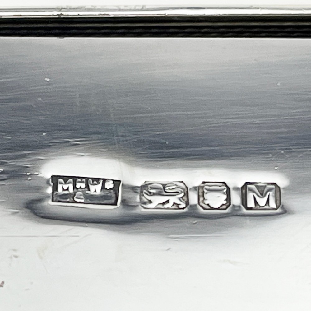 A rectangular sterling silver box featuring an engine-turned patterned lid, a central rectangular cartouche, and four stepped bracket feet. View IX