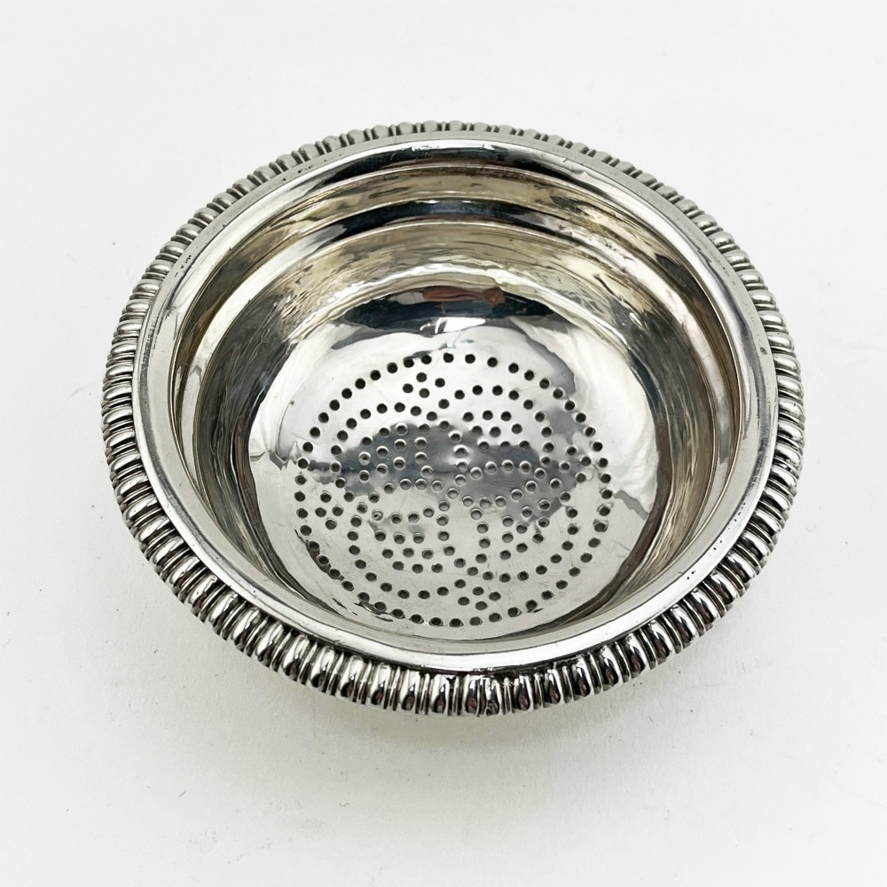A Georgian sterling silver wine funnel resting on a beaded circular drip tray with visible hallmarks. View V