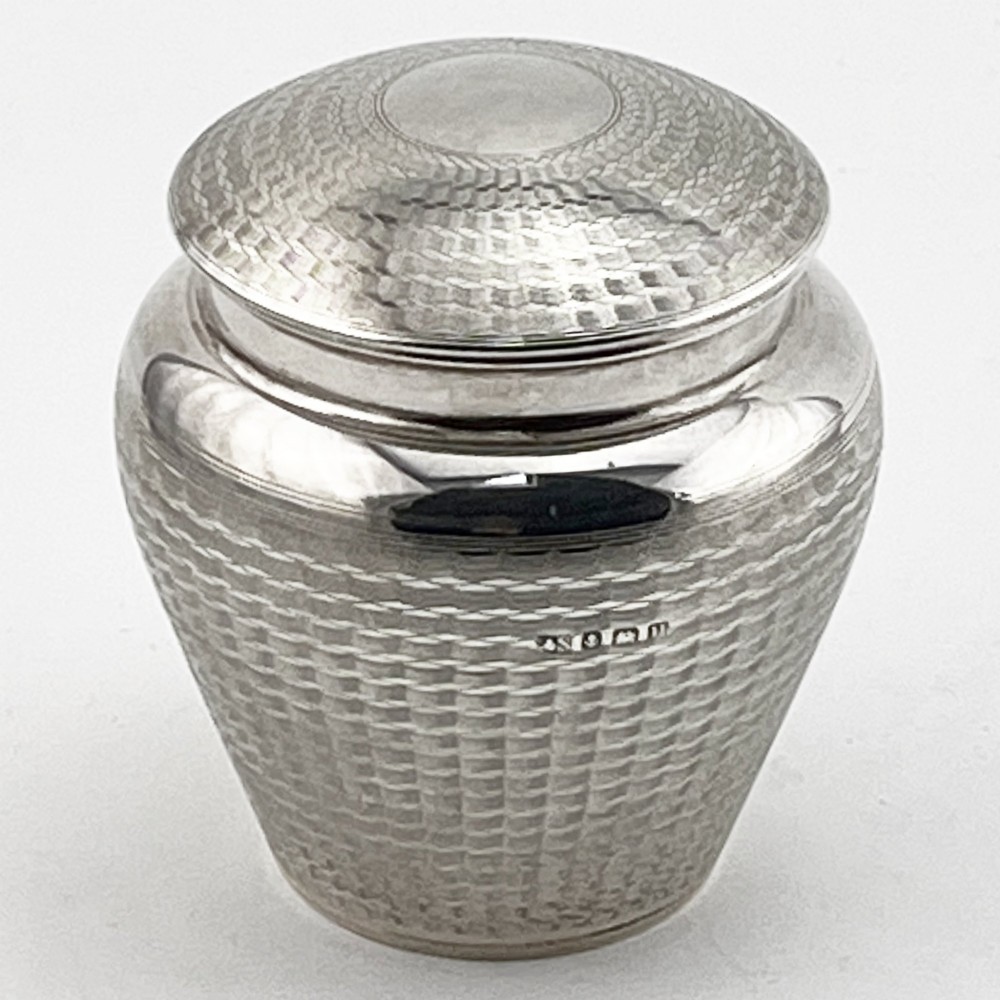 A rounded sterling silver tea caddy featuring a woven engine-turned textured pattern across the body and fitted circular lid, displaying British hallmarks.