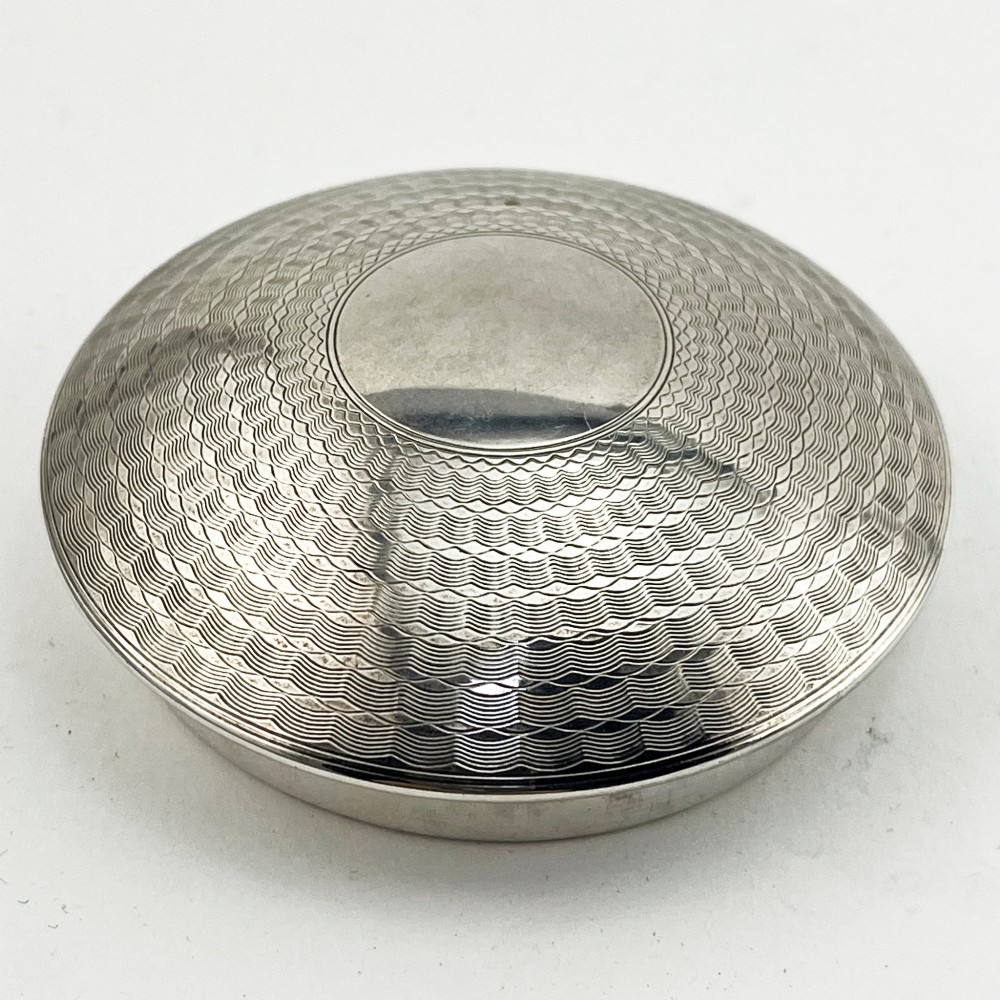 A rounded sterling silver tea caddy featuring a woven engine-turned textured pattern across the body and fitted circular lid, displaying British hallmarks. View II