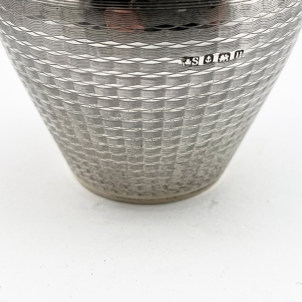 A rounded sterling silver tea caddy featuring a woven engine-turned textured pattern across the body and fitted circular lid, displaying British hallmarks. View III