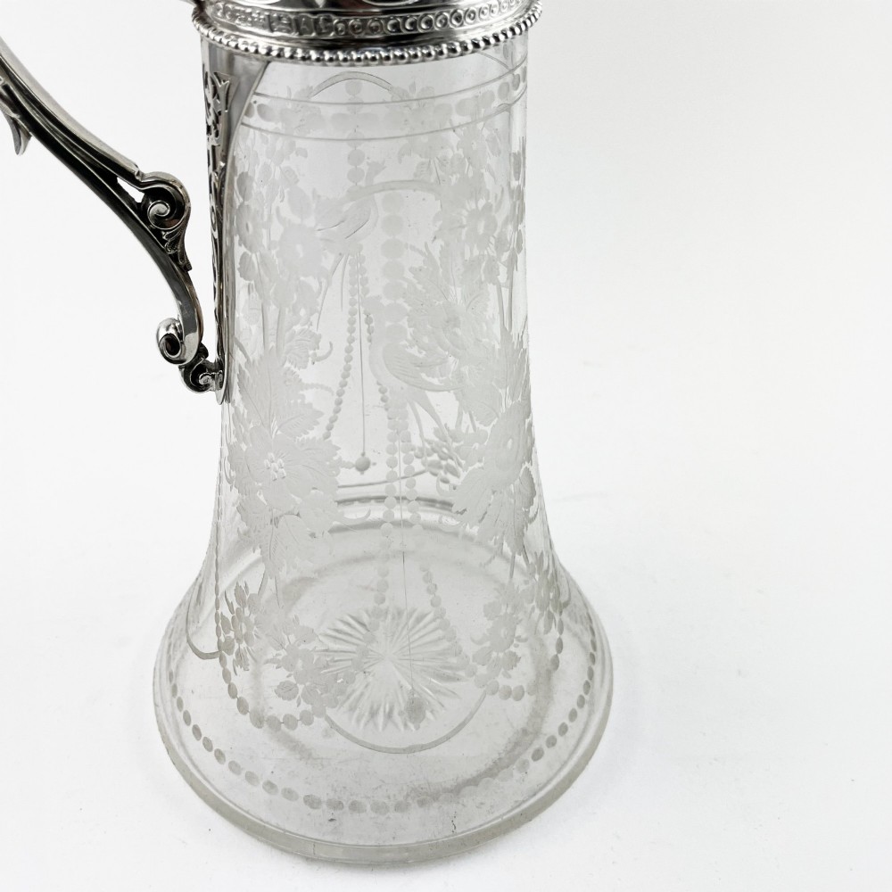 A Victorian sterling silver-mounted clear glass claret jug with floral glass etching, chased silver neck collar, and angular silver handle. View VIII