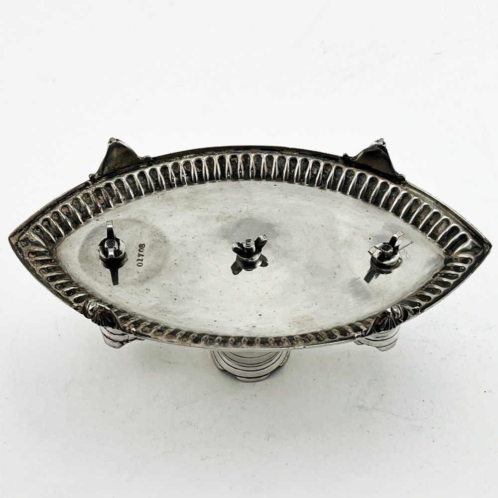 A silver-plated table cigar lighter featuring three horizontal-ribbed conical towers set on an oval tray with a gadrooned border and scrolled feet. View V