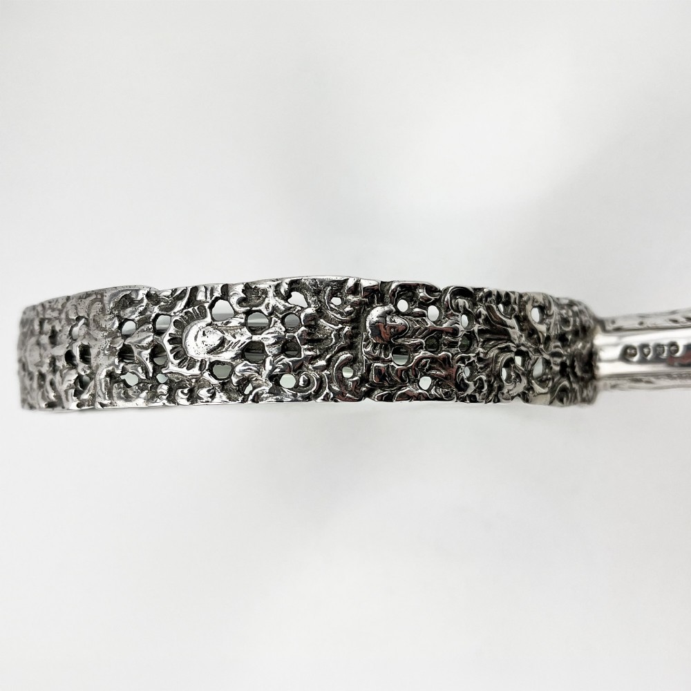 An antique Victorian sterling silver magnifying glass featuring an intricately chased handle and a pierced decorative circular silver rim. View III