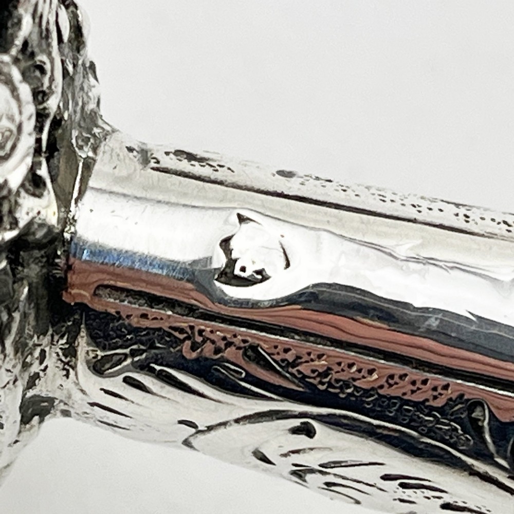 An antique Victorian sterling silver magnifying glass featuring an intricately chased handle and a pierced decorative circular silver rim. View VII
