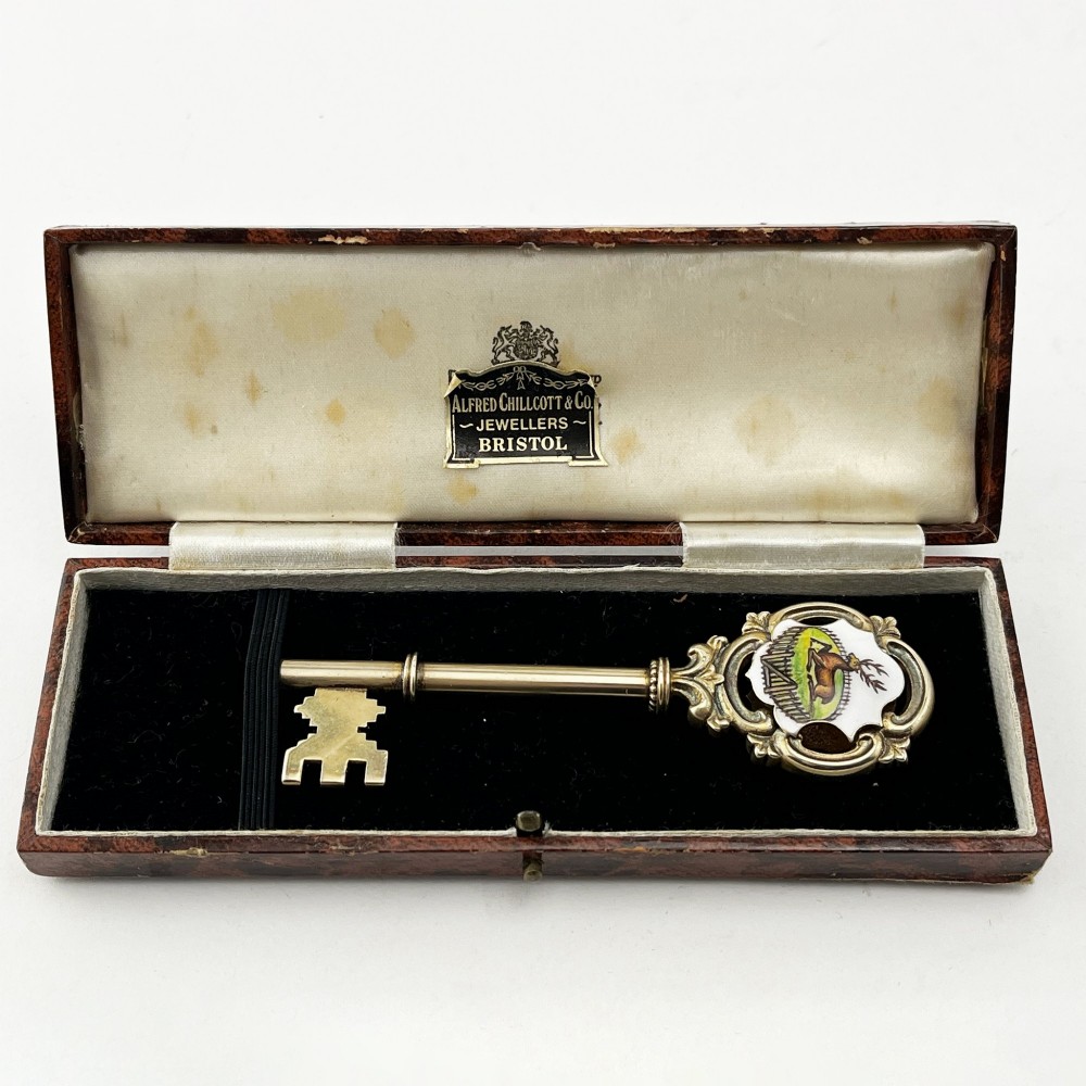 An antique sterling silver presentation key with a stag enamel crest displayed inside its original velvet-lined presentation box.
