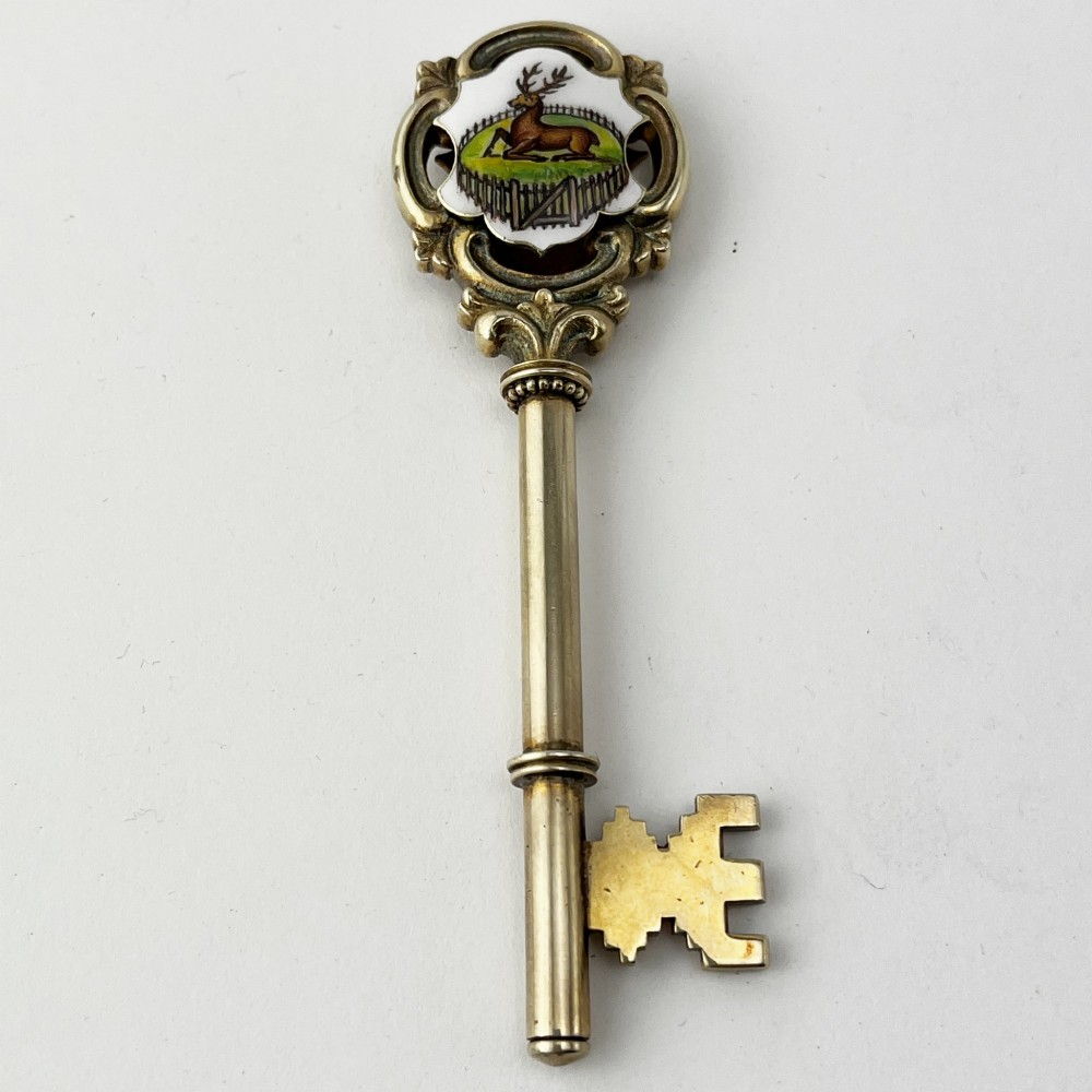 An antique sterling silver presentation key with a stag enamel crest displayed inside its original velvet-lined presentation box. View II
