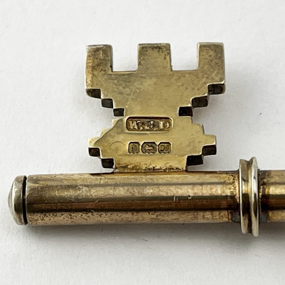 An antique sterling silver presentation key with a stag enamel crest displayed inside its original velvet-lined presentation box. View V