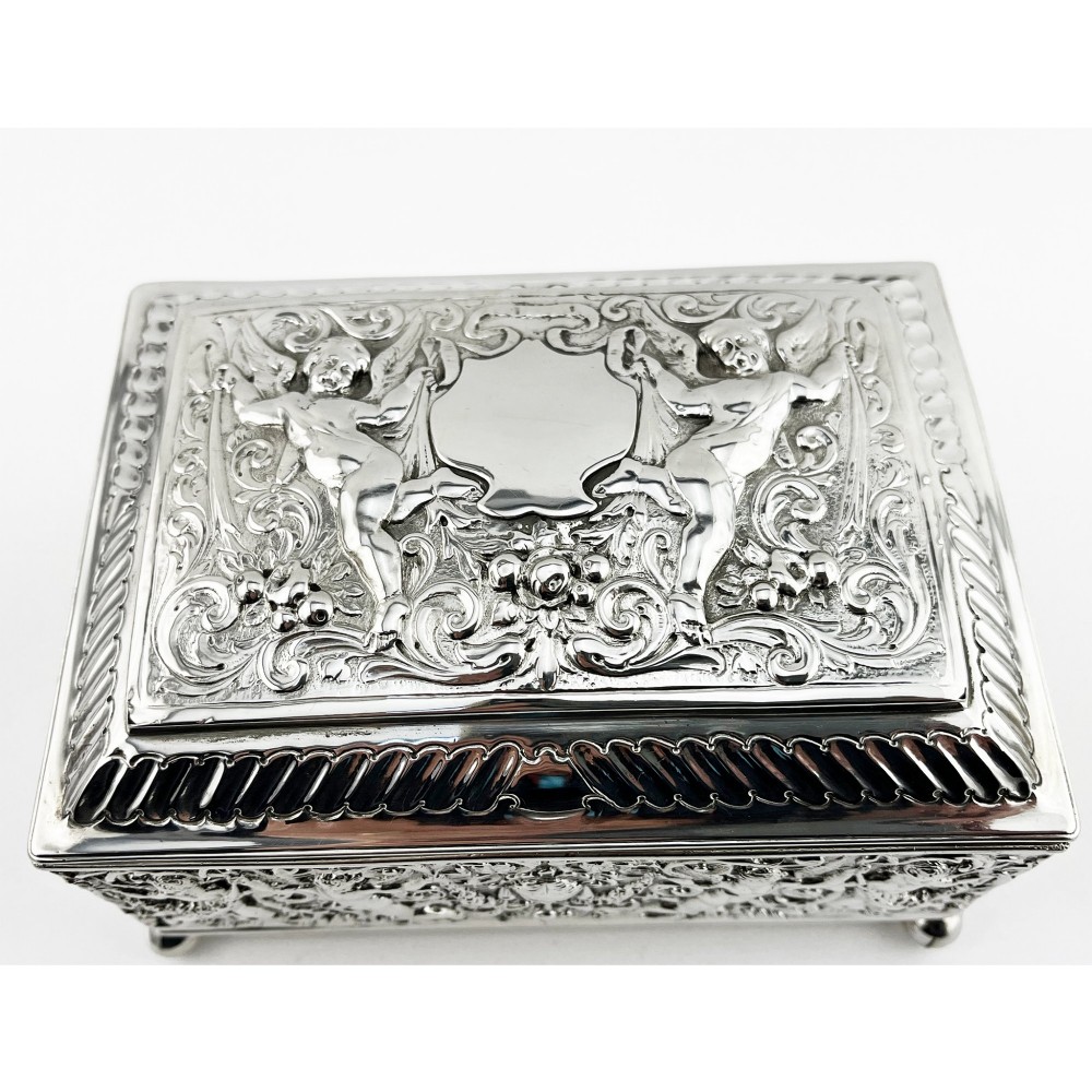 A rectangular Victorian sterling silver trinket box decorated with detailed repousse cherubs and floral scrolls, supported by four ball feet. View III