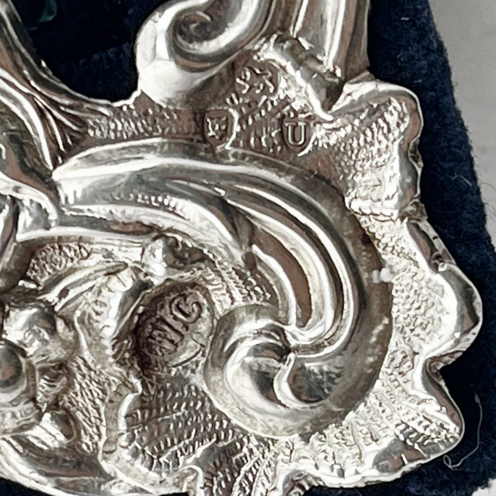An ornate Victorian sterling silver double photo frame featuring elaborate pierced scrollwork, cherubs, and two heart-shaped apertures backed with dark velvet. View VI