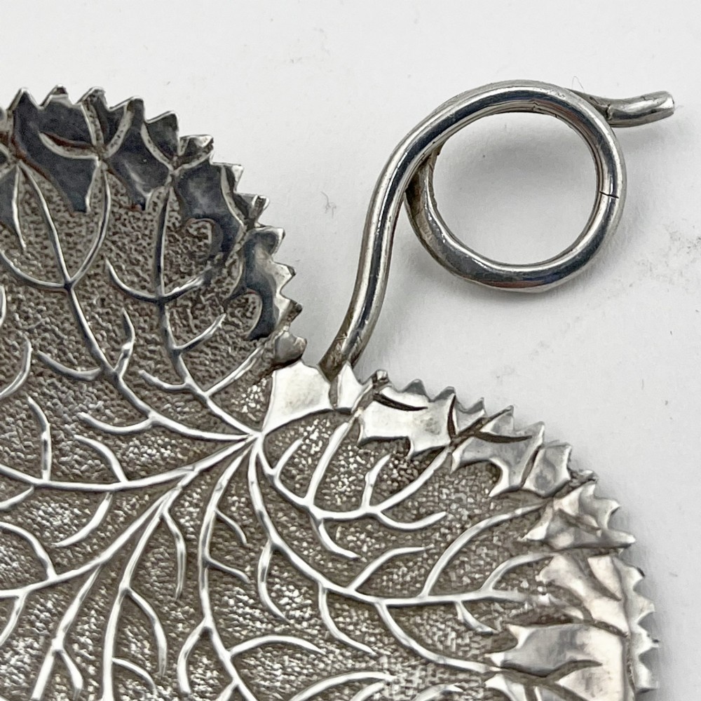 A Georgian sterling silver tea caddy spoon fashioned in the shape of a serrated leaf with engraved vein detailing and a coiled ring handle. View III