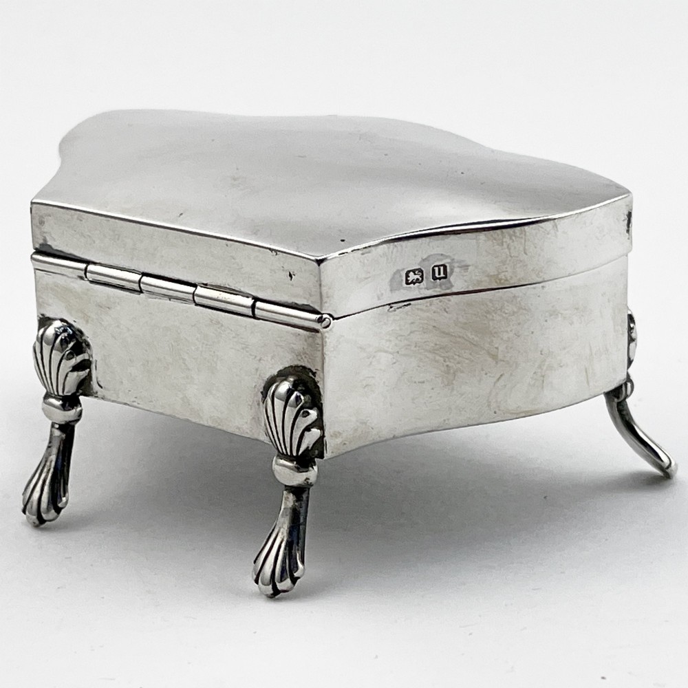 A polished sterling silver trinket box featuring a contoured lid and four shell-motif feet. View III