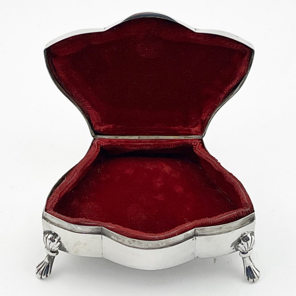 A polished sterling silver trinket box featuring a contoured lid and four shell-motif feet. View IV