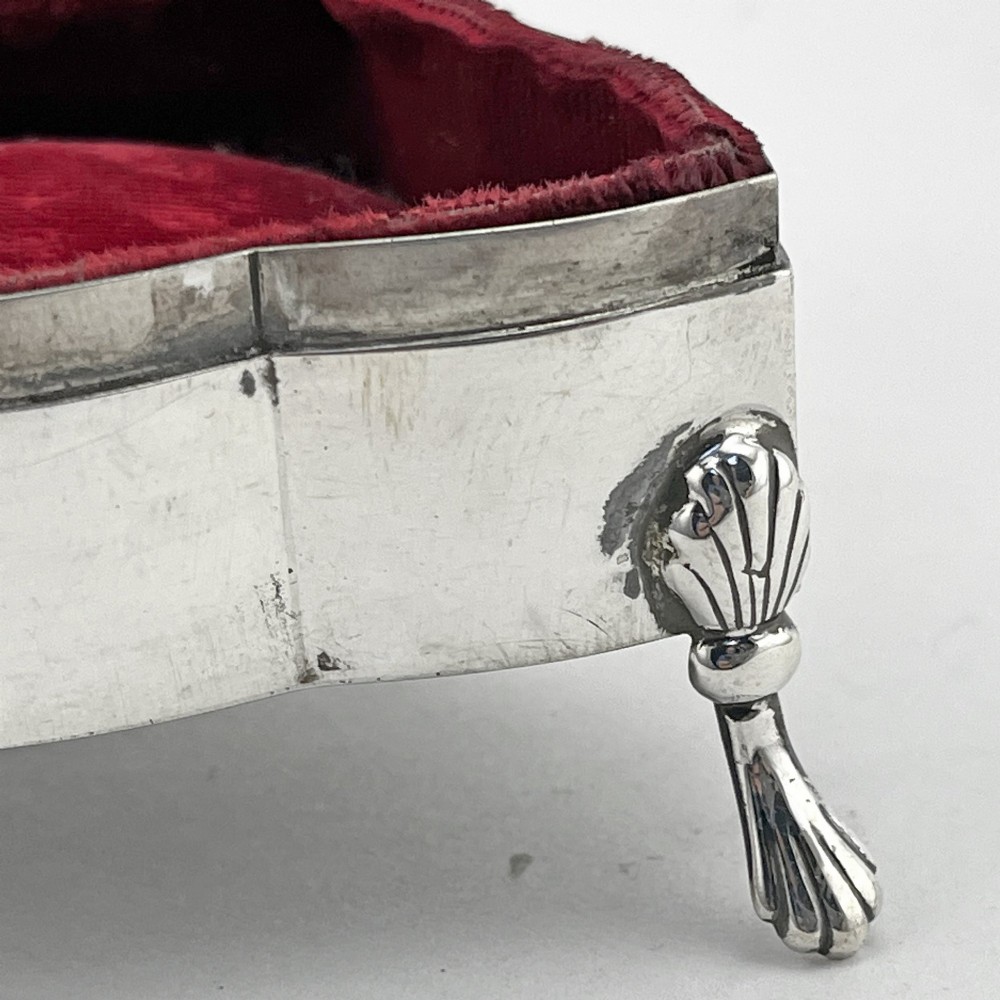 A polished sterling silver trinket box featuring a contoured lid and four shell-motif feet. View V