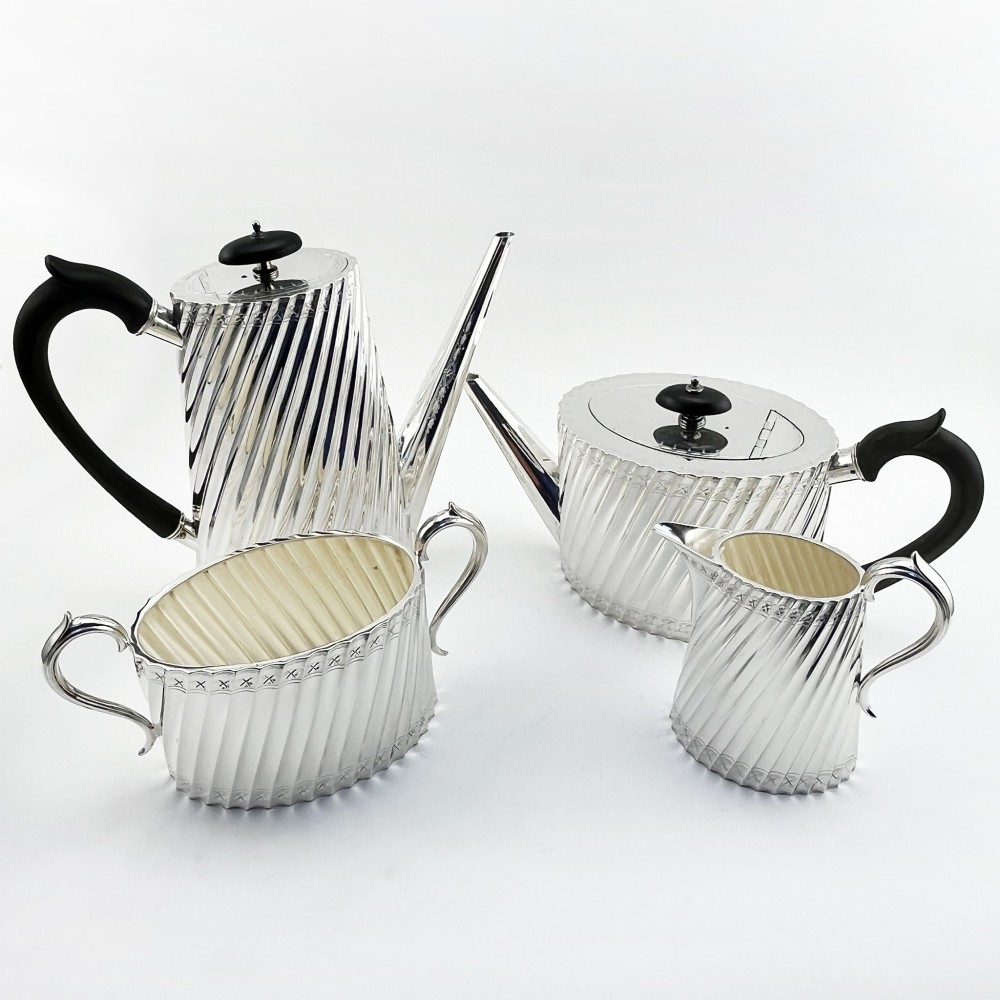 A four-piece Victorian silver-plated tea and coffee set featuring diagonal fluted body detailing and ebonised handles.