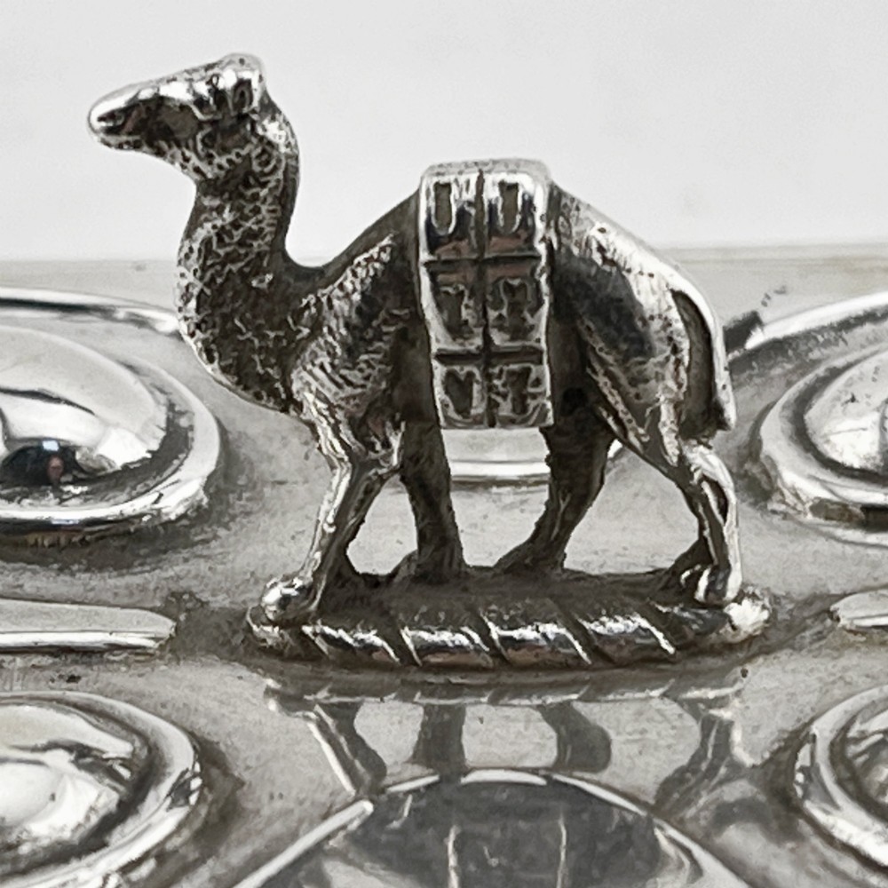 A square sterling silver trinket casket featuring a camel finial on the lid and detailed desert relief panels along the sides. View III