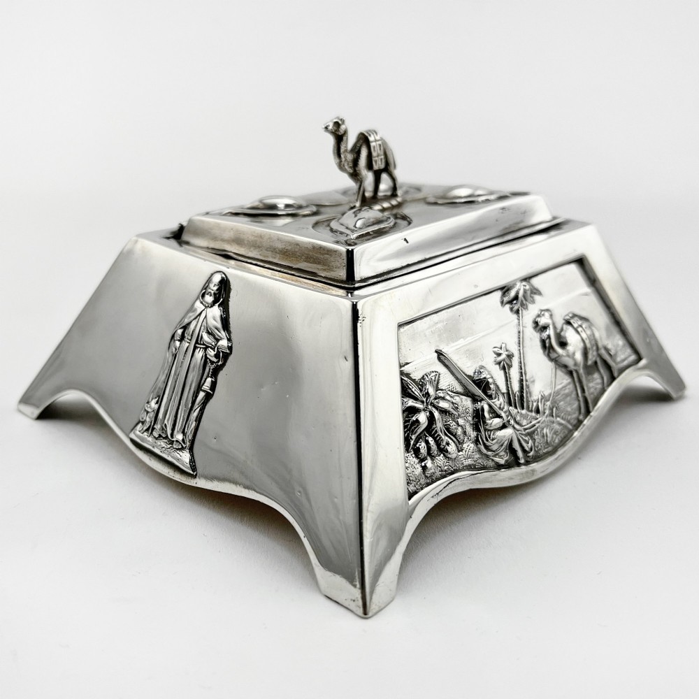 A square sterling silver trinket casket featuring a camel finial on the lid and detailed desert relief panels along the sides. View VI