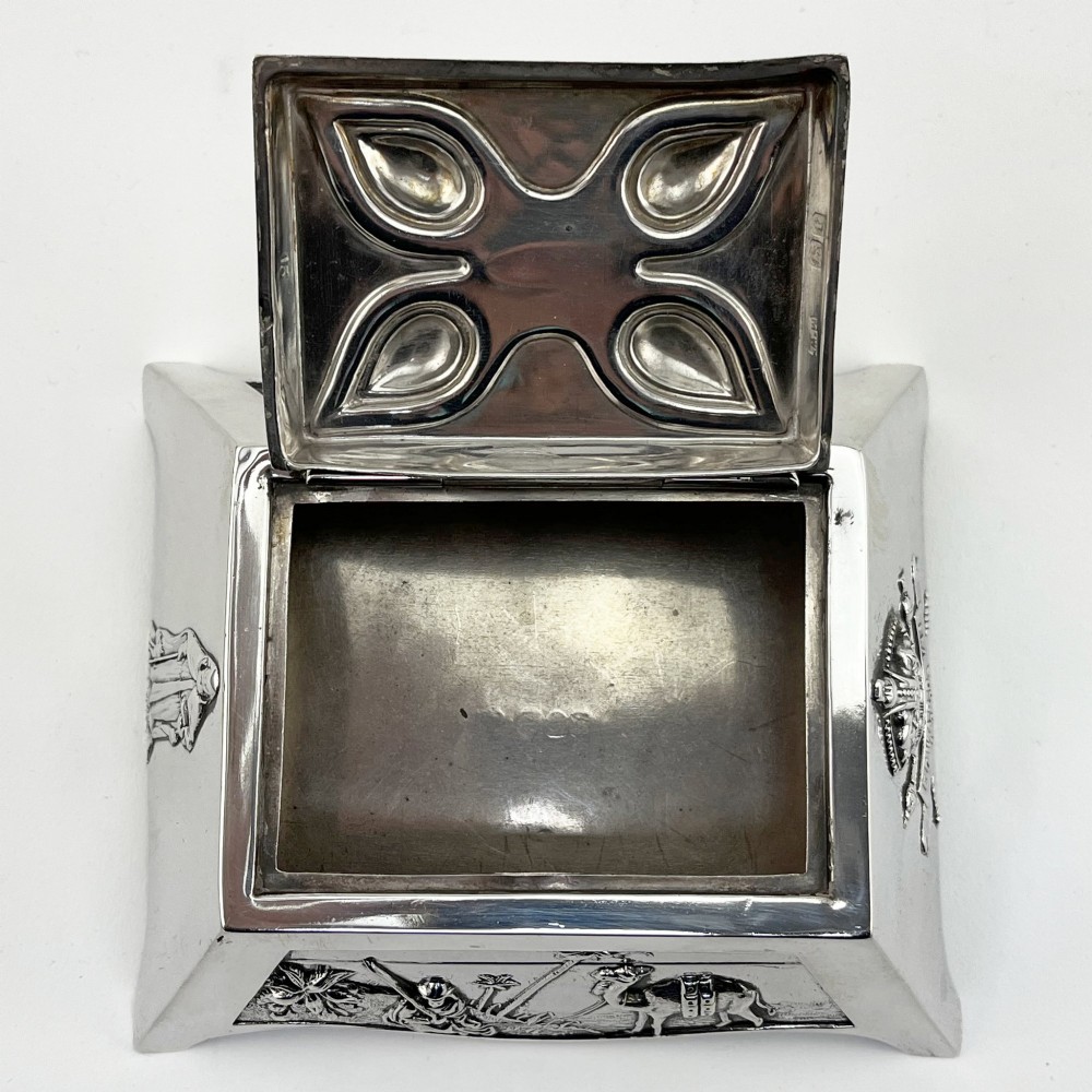 A square sterling silver trinket casket featuring a camel finial on the lid and detailed desert relief panels along the sides. View VII
