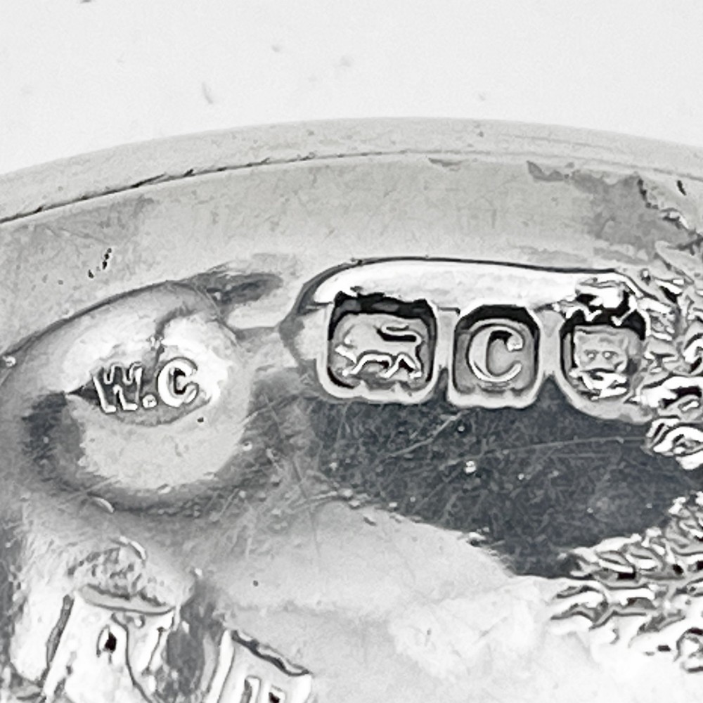 A circular sterling silver trinket box featuring a repousse relief on the lid depicting a seated bagpipe player and figures in a landscape. View VI