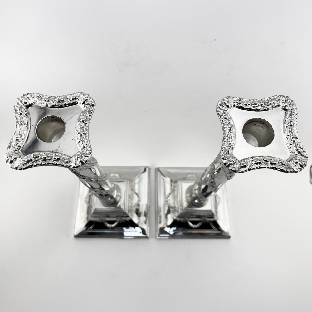 A pair of silver-plated column candlesticks featuring Corinthian capitals, spiral foliate garlands along the shafts, and square stepped bases. View II