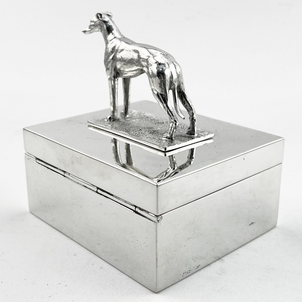A rectangular silver-plated box featuring a polished finish and a sculpted figure of a standing greyhound attached to the lid. View IV
