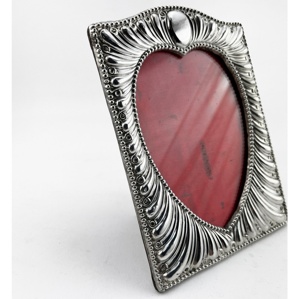 A Victorian sterling silver photo frame featuring repousse fluted patterns, a beaded border, and a heart-shaped picture aperture with a red fabric interior. View III
