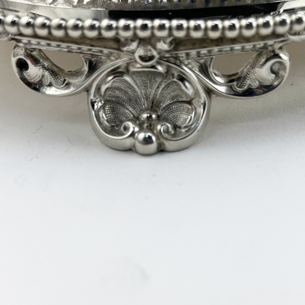 An oval Victorian silver-plated biscuit box featuring reticulated fretwork sides, an engraved lid with a dog finial, and a beaded footed base. View VI
