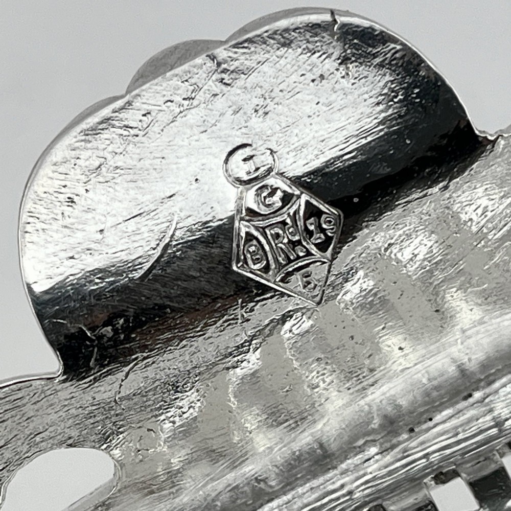 An oval Victorian silver-plated biscuit box featuring reticulated fretwork sides, an engraved lid with a dog finial, and a beaded footed base. View VII