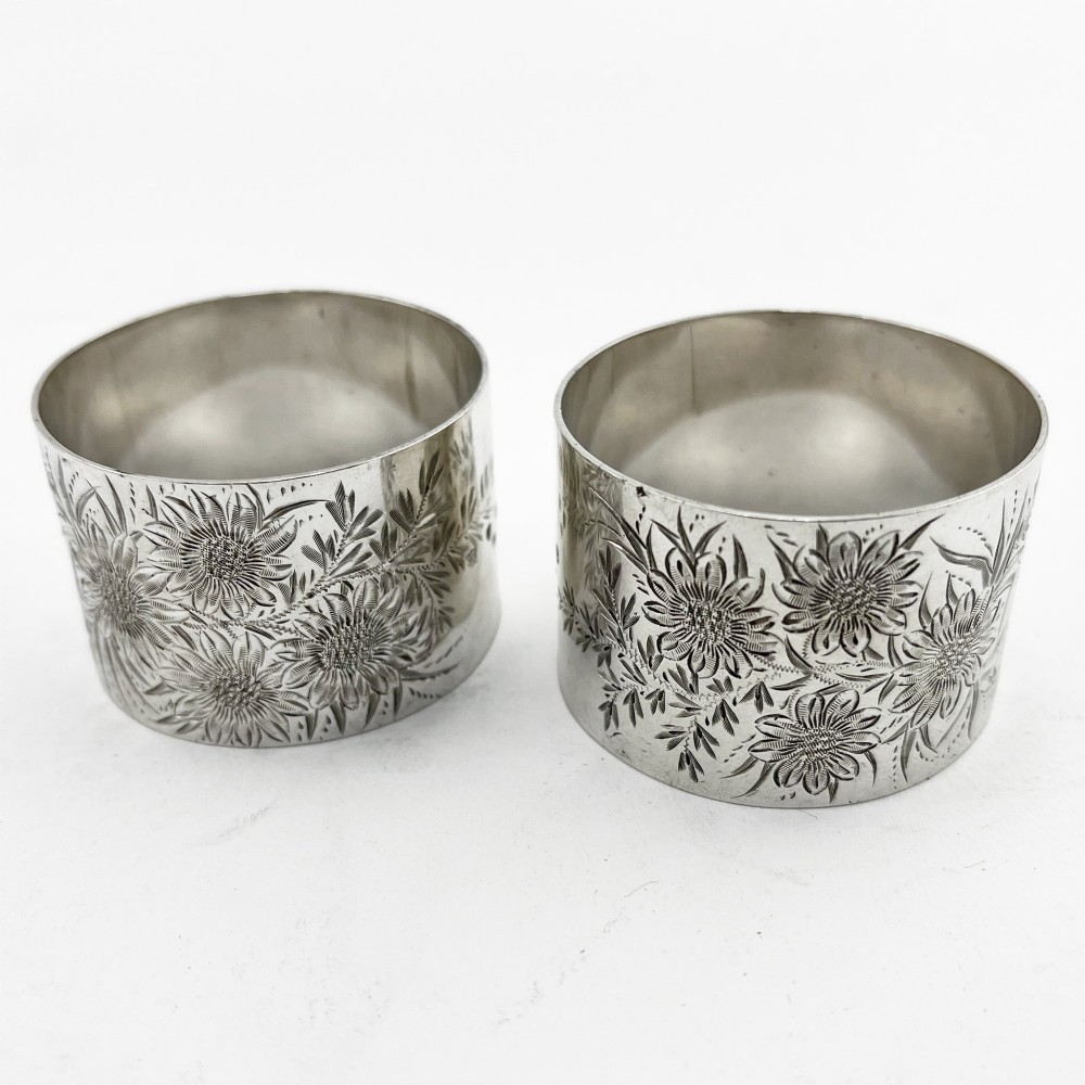 A pair of engraved Victorian sterling silver napkin rings numbered 1 and 2 inside a fitted velvet display case. View II