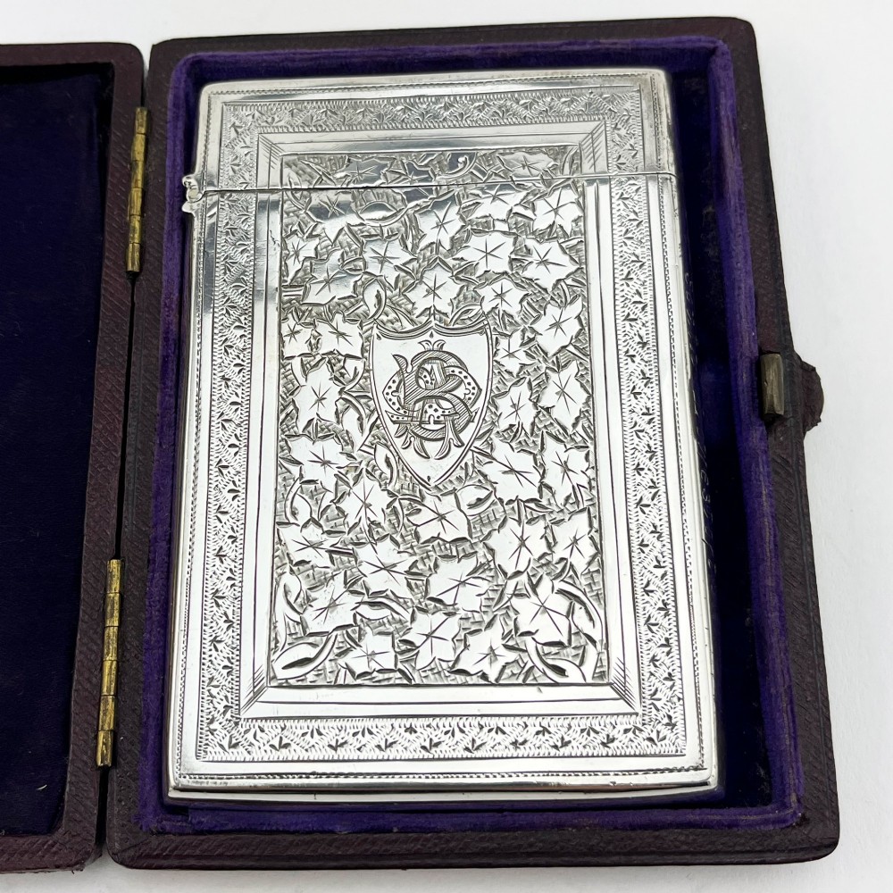 An engraved Victorian sterling silver visiting card case with ivy foliage patterning, seated inside a purple velvet-lined presentation box. View II