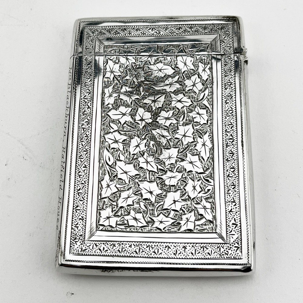 An engraved Victorian sterling silver visiting card case with ivy foliage patterning, seated inside a purple velvet-lined presentation box. View IV