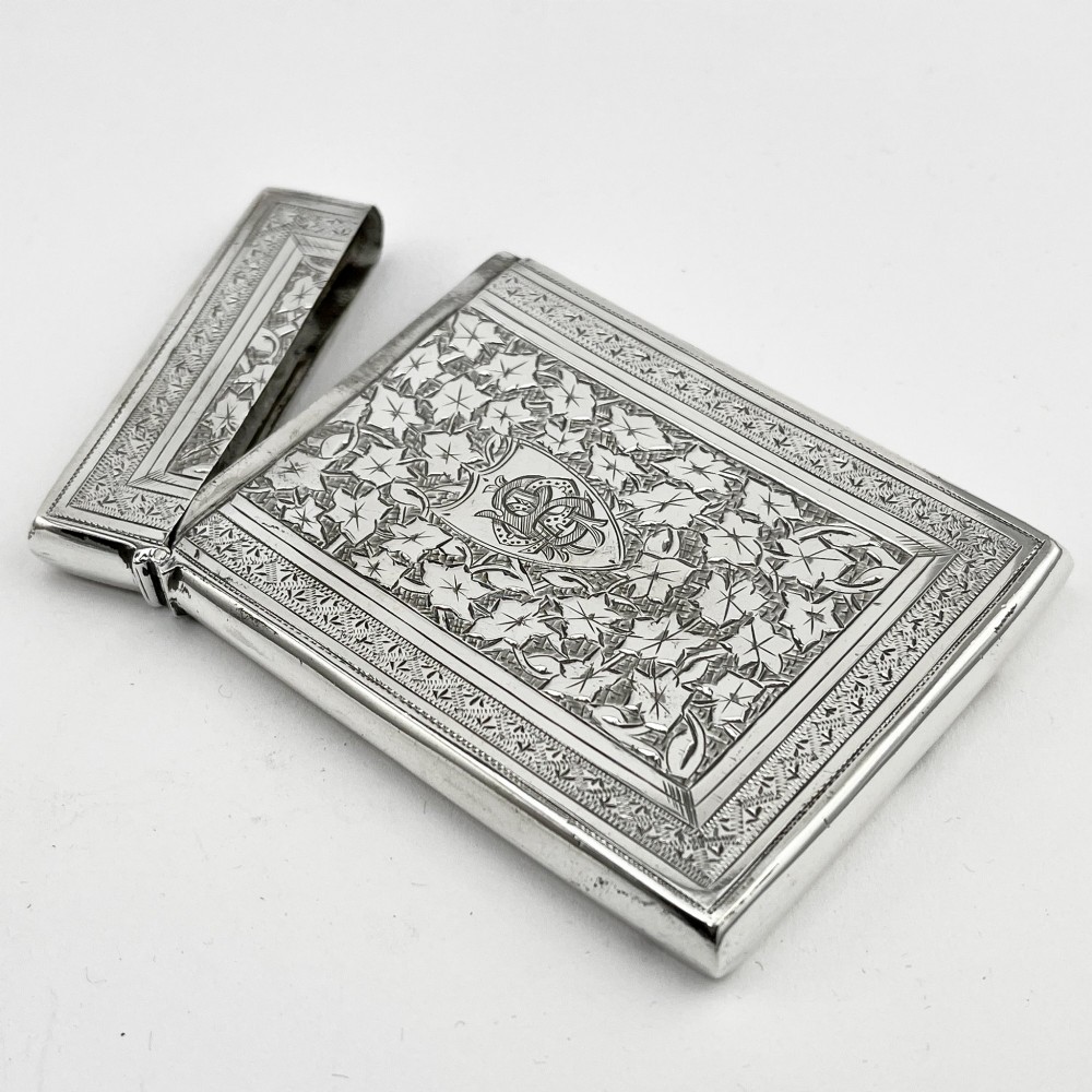 An engraved Victorian sterling silver visiting card case with ivy foliage patterning, seated inside a purple velvet-lined presentation box. View V