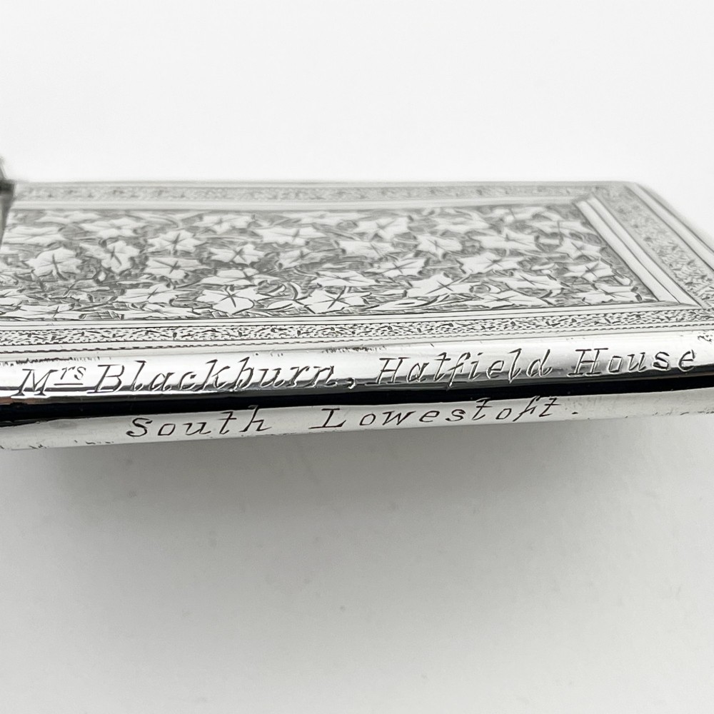 An engraved Victorian sterling silver visiting card case with ivy foliage patterning, seated inside a purple velvet-lined presentation box. View VI