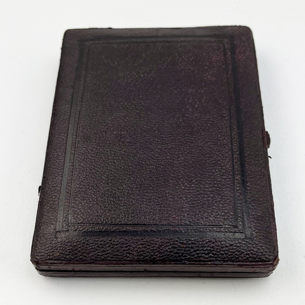 An engraved Victorian sterling silver visiting card case with ivy foliage patterning, seated inside a purple velvet-lined presentation box. View IX