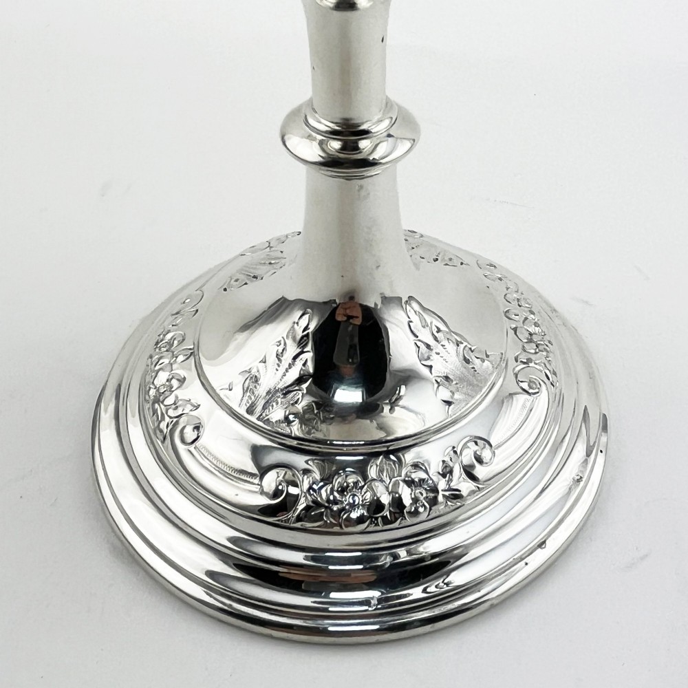 A silver-plated Victorian trophy cup featuring chased scrollwork, twin high-arched loop handles, and a stepped circular pedestal base. View V