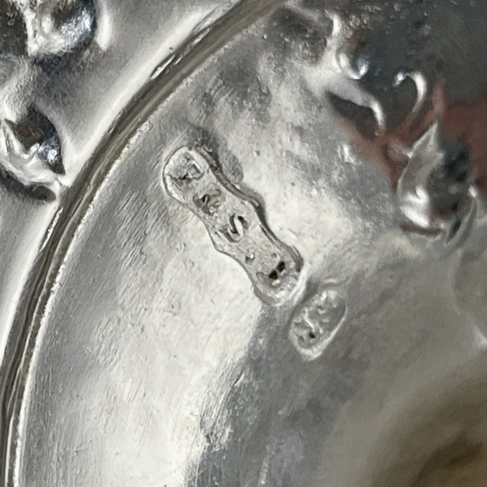 A silver-plated Victorian trophy cup featuring chased scrollwork, twin high-arched loop handles, and a stepped circular pedestal base. View VII